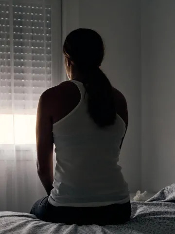 mulher-sentada-na-cama-de-costas-olhando-para-a-janela-abuso-sexual-abuso-assedio-estupro-mulher-tri